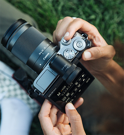  the Canon EOS M6 Mark II held in a hand, with the display tilted by the other hand  